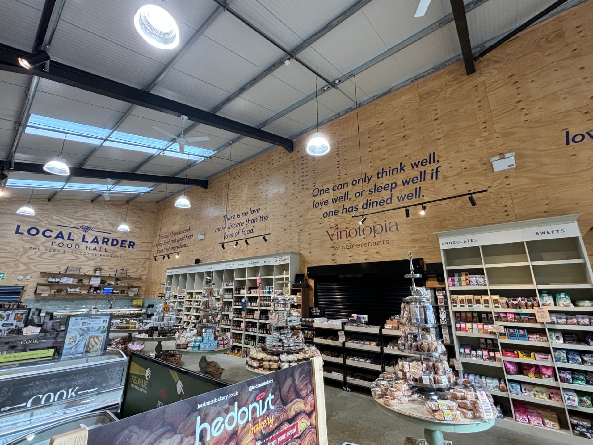 Retail food hall with black track lighting above timber display units