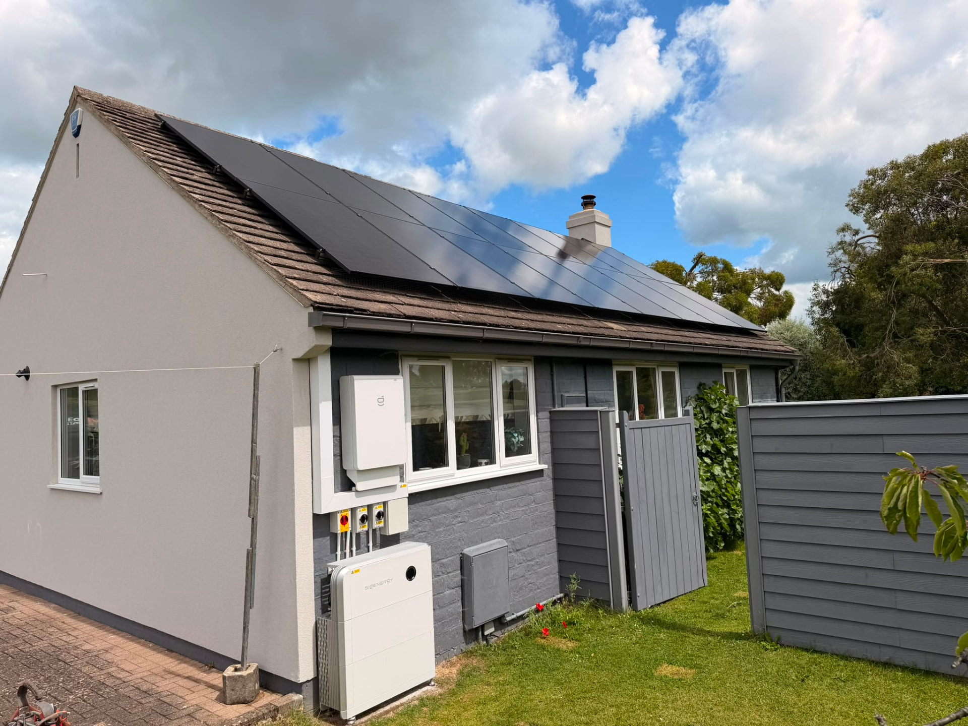 Gable end of a house with solar panels above and battery storage equipment below