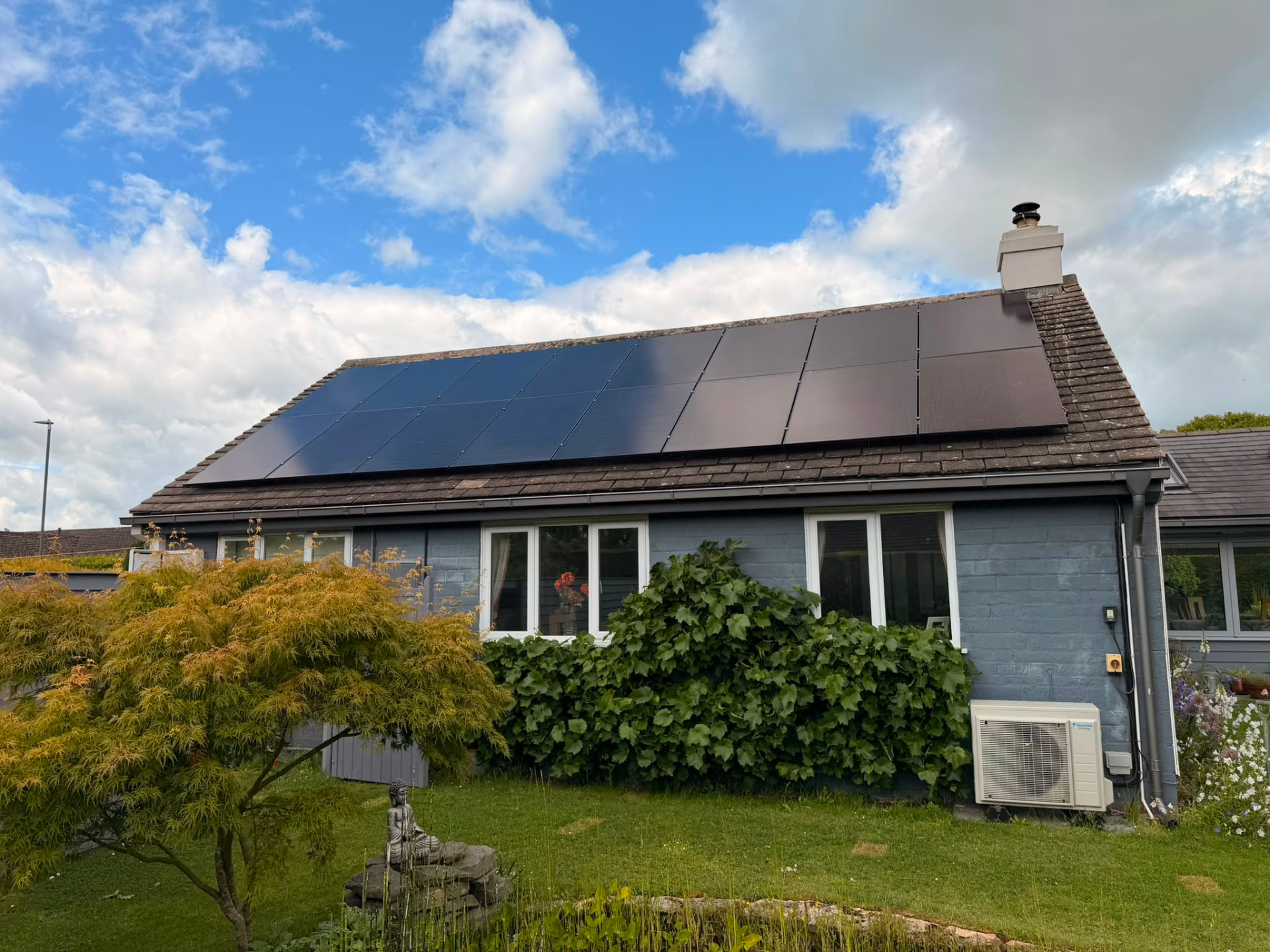 Solar panels on a Cotswold stone roof beside a battery storage cabinet