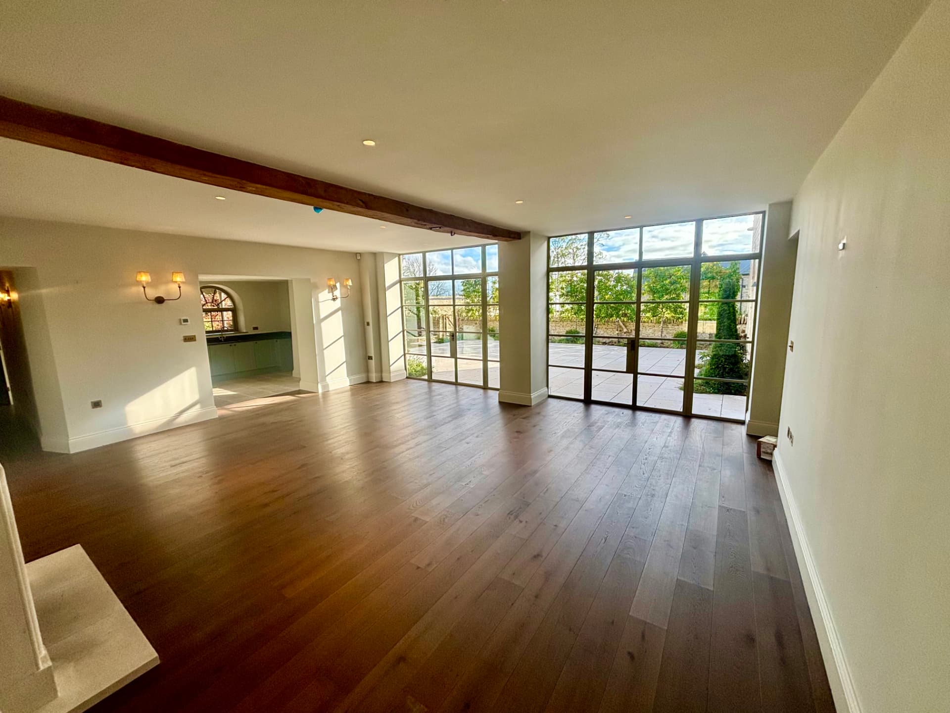 Open plan reception room with full-height glazing and wall lights