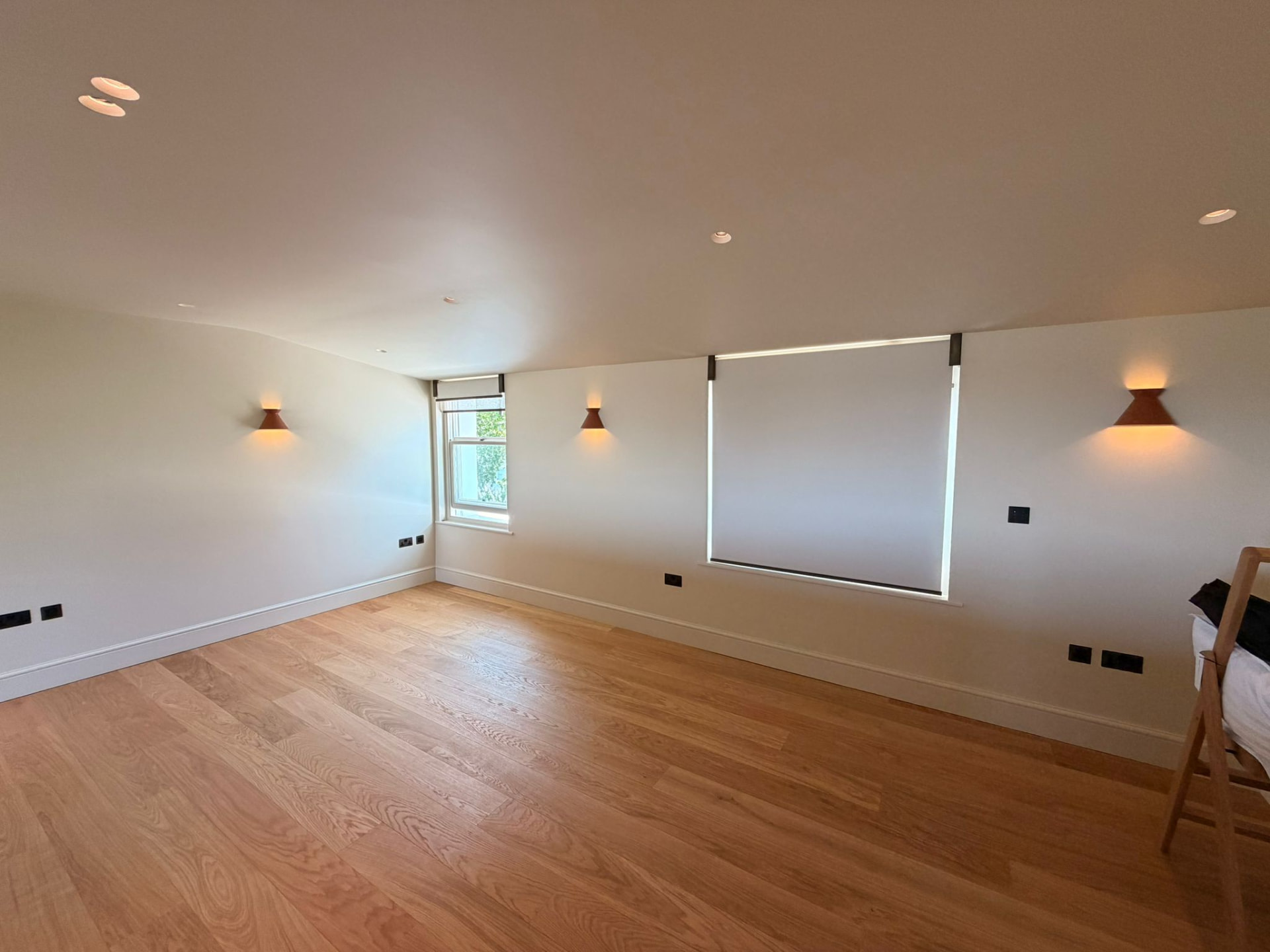Bedroom with wall uplights, recessed downlights and roller blinds
