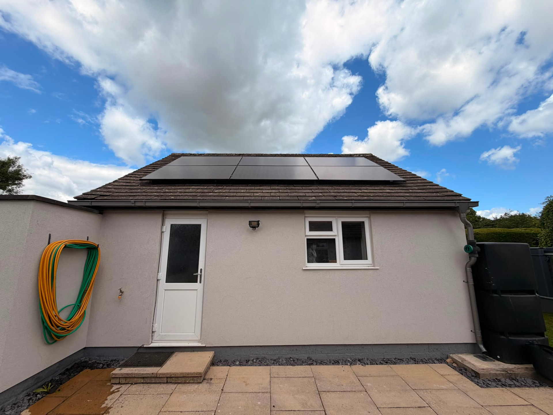 Rear elevation of a rendered outbuilding with roof-mounted solar panels
