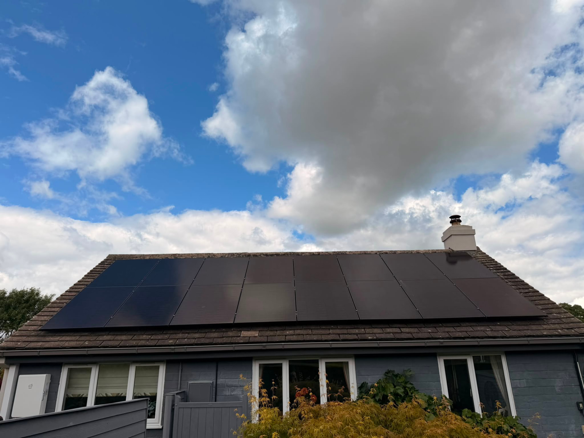 Full-width solar array across the main house roof beside a chimney